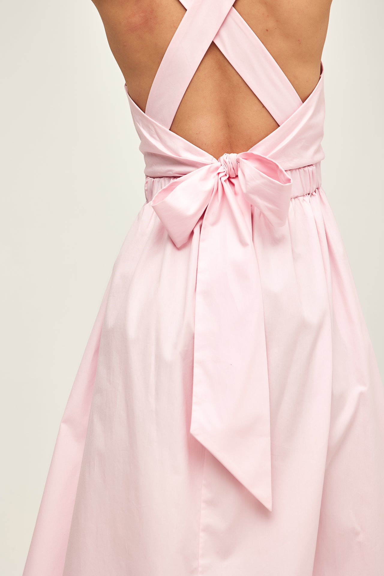 model wearing a baby pink dress with a big bow back close up